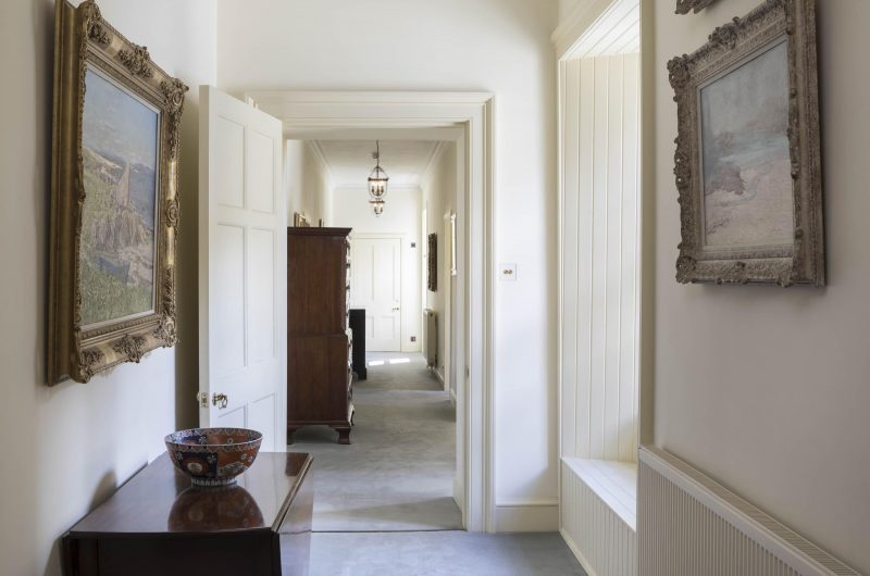 Interior view of corridor at Country House, surveyed and renovated by Harry Taylor & Co, Perth. Heritage Paint colours and molding, with antiques and paintings on walls.