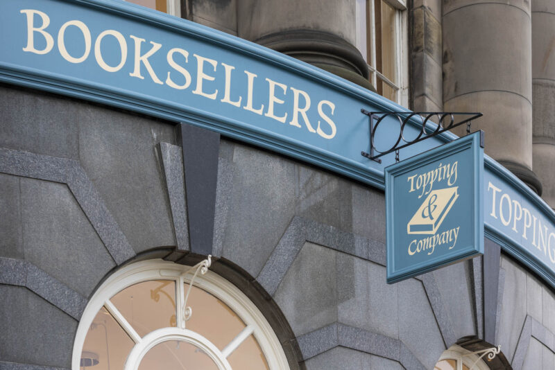Painted signage in blue and cream at Topping and Co Booksellers, Edinburgh. Traditionally handpainted with a swing sign.